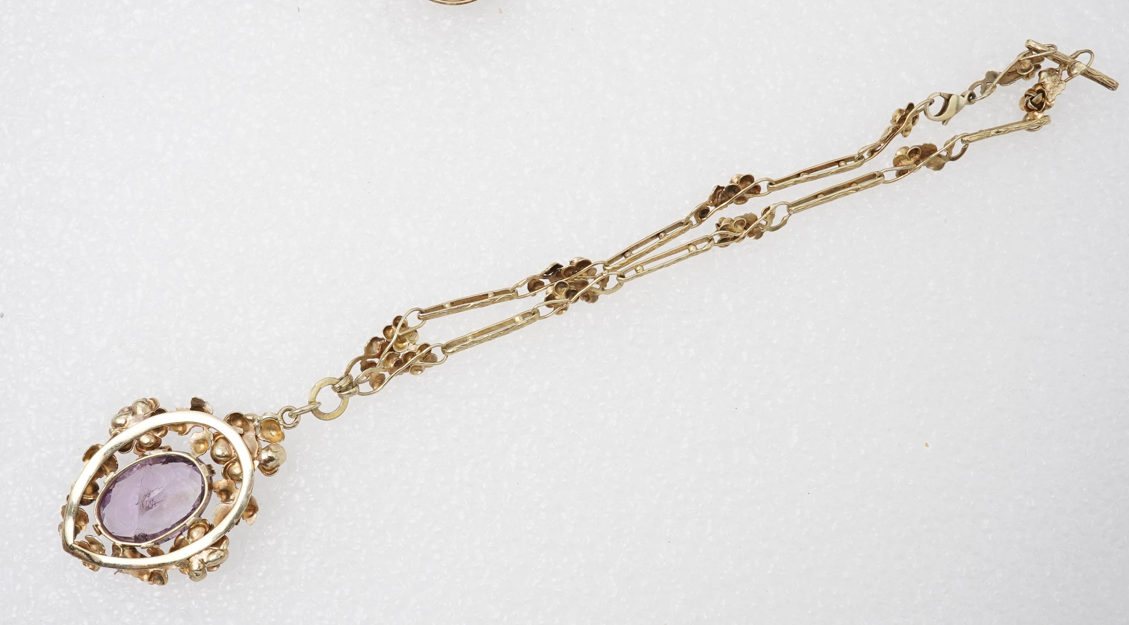 An amethyst ring, necklace and pendant, comprising: an oval amethyst set in a floral gilt silver necklace, length 32cm; an oval amethyst and seed pearl pendant, length 3.7cm; and a ring set with an oval amethyst, mounted